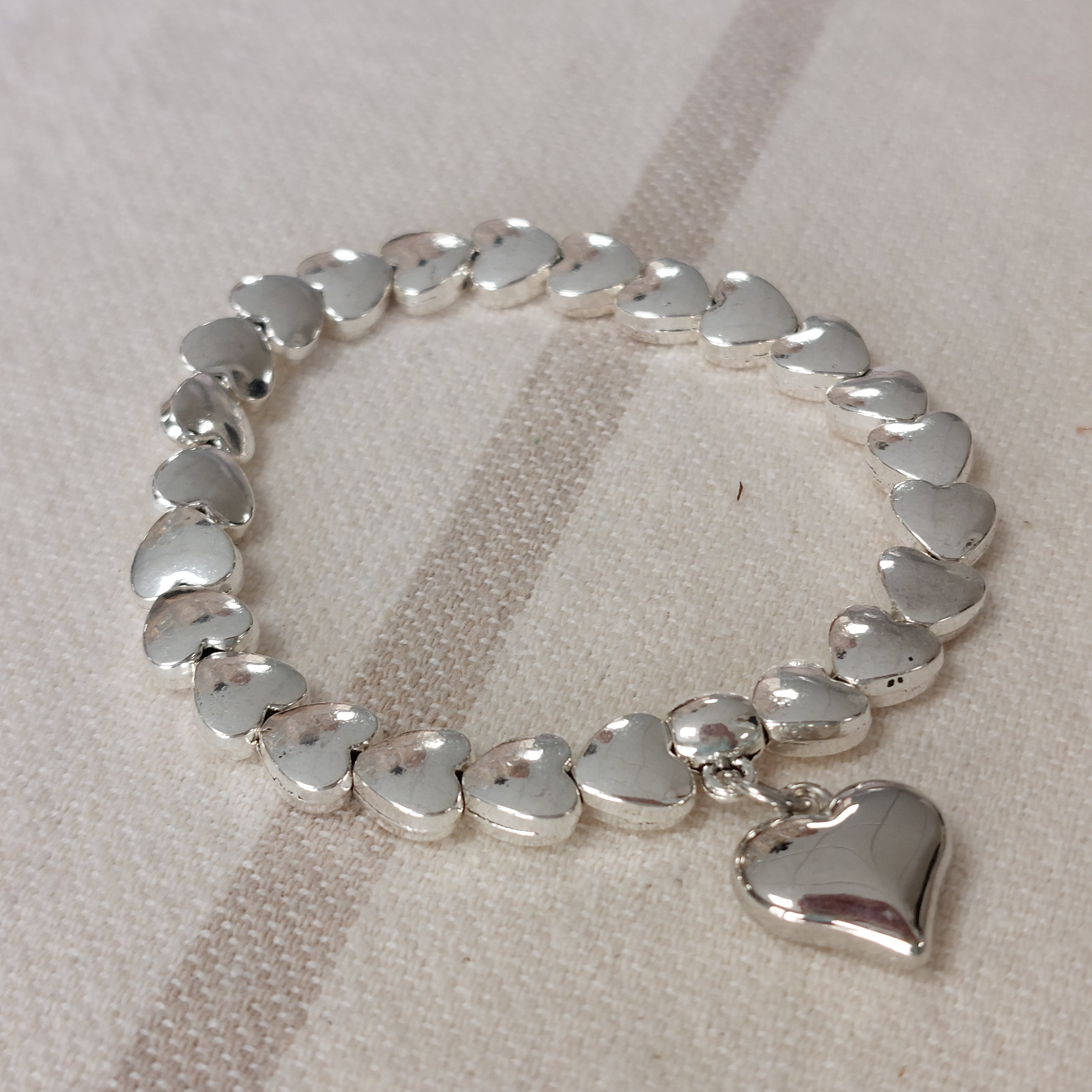 Bracelet élastiqué constitué de perles aciers en forme de petits coeurs bombés et fini par une pampille aussi en forme de coeur bubble sur sausset les pins