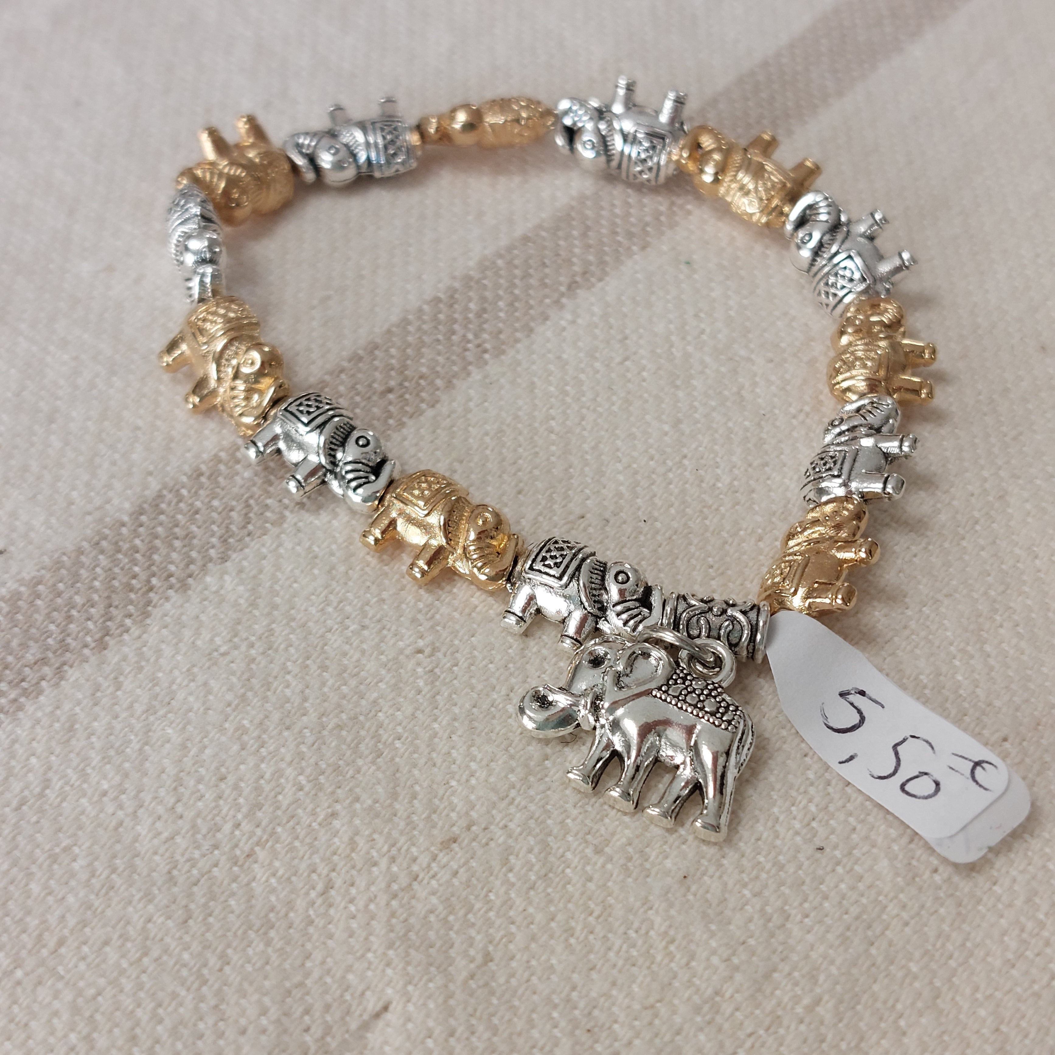 Bracelet élastiqué constitué de perles aciers en forme de petits éléphants dorés et argentés et fini par une pampille aussi en forme d'éléphant argent sur carry le rouet