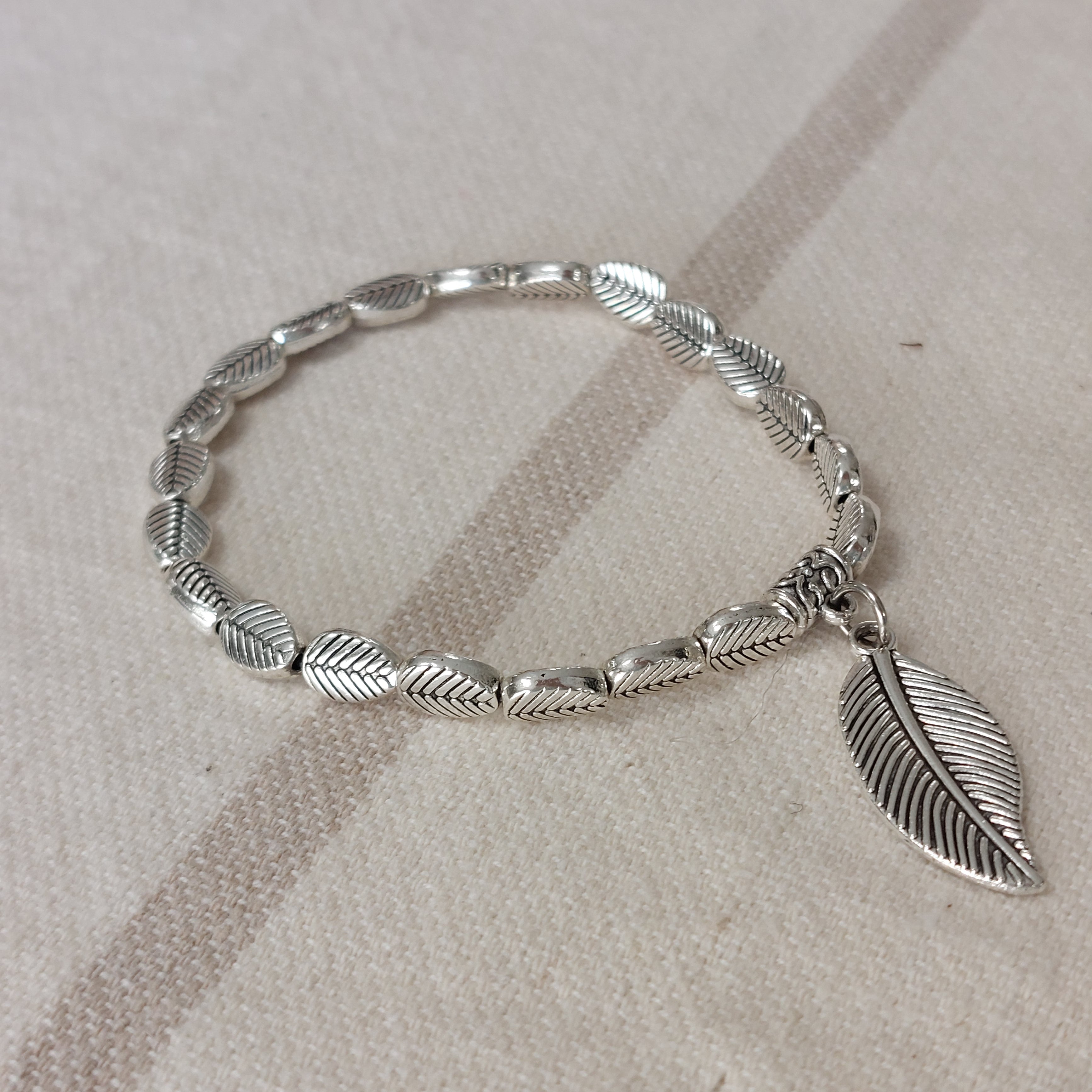 Bracelet élastiqué constitué de perles aciers en forme de petites feuilles rainurées et fini par une pampille aussi en forme de feuille rainurée en noir sur marignane