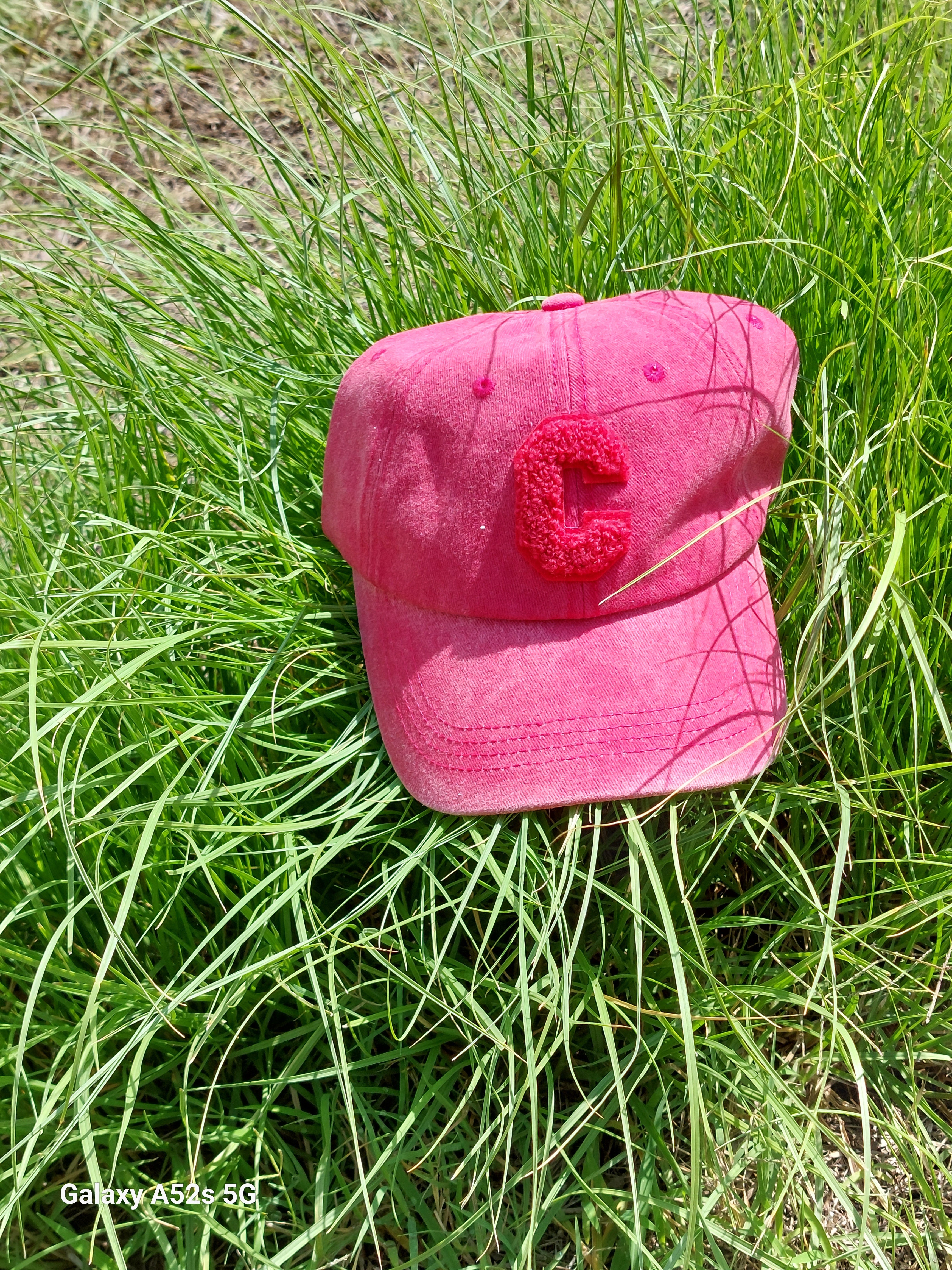 Casquette Ponteau est en tissus uni de forme base Ball coloris rouge délavé, réglable par l'arrière elle a un C majuscule en moumoute blanche sur le devantet une petite bille sur le dessus sur carry le rouet