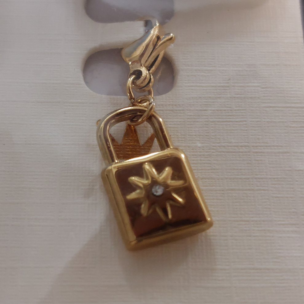 charm ou breloque avec un petit fermoir pour ajouter à un collier où à un bracelet en accumulation personnalisé. il represente un cadenas doré et son petit brillant en acier inoxydable sur marignane