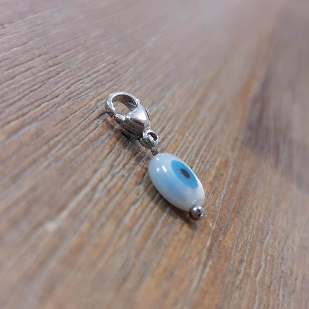 charm ou breloque avec un petit fermoir pour ajouter à un collier où à un bracelet en accumulation personnalisé. il represente un oeil de Ste lucie blanc et bleu en acier inoxydable sur marignane