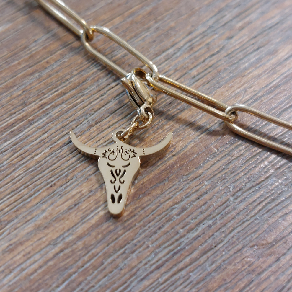 charm ou breloque avec un petit fermoir pour ajouter à un collier où à un bracelet en accumulation personnalisé. il represente une tete de buffle doré et ajouré en acier inoxydable sur carry le rouet