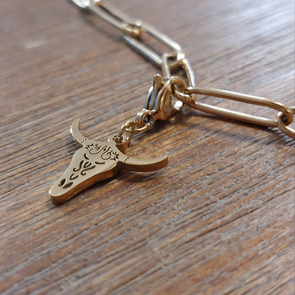 charm ou breloque avec un petit fermoir pour ajouter à un collier où à un bracelet en accumulation personnalisé. il represente une tete de buffle ajourée et dorée en acier inoxydable sur martgues