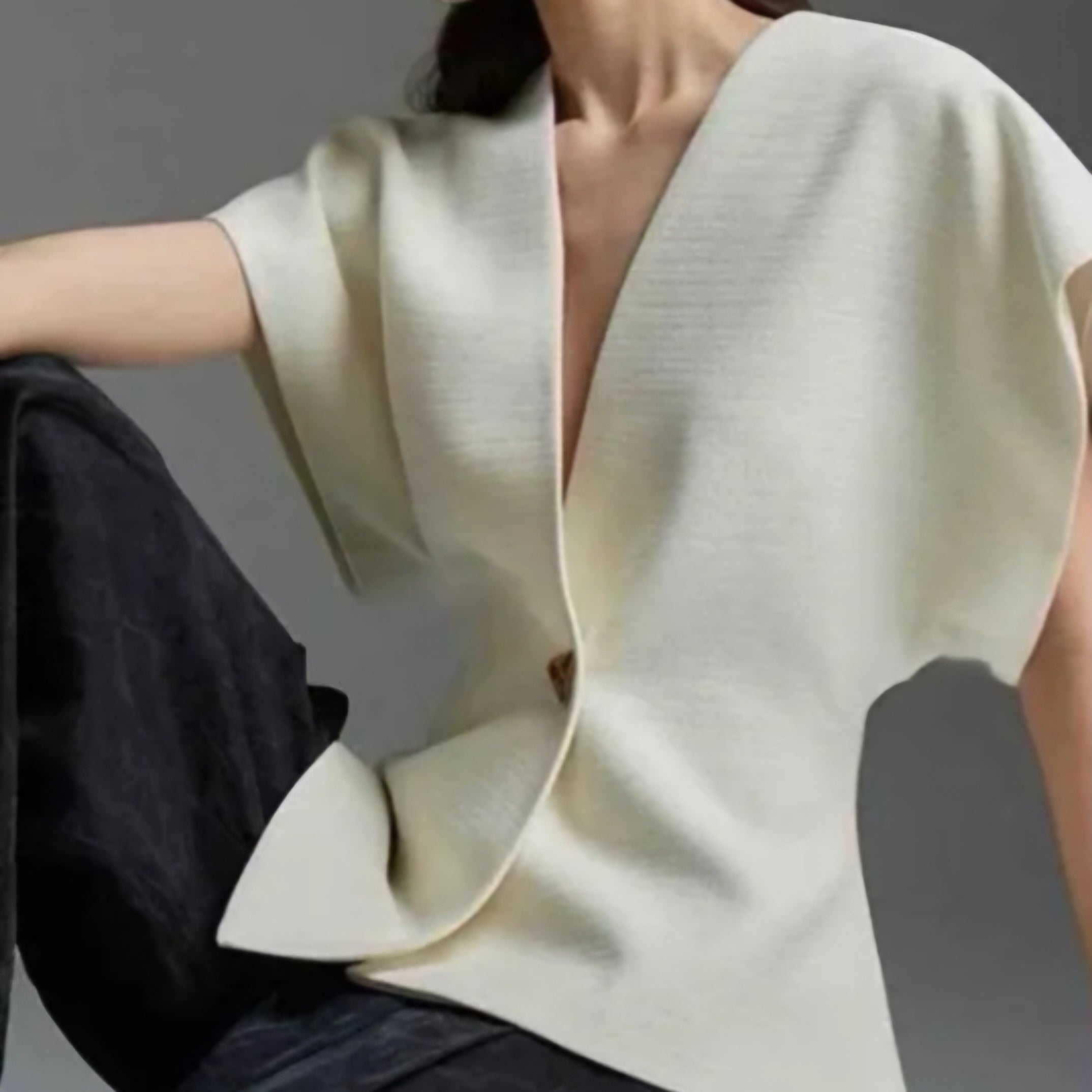 Femme portant le gilet GALA asymétrique sans manches en coloris écru avec bouton doré, taille unique 36-42