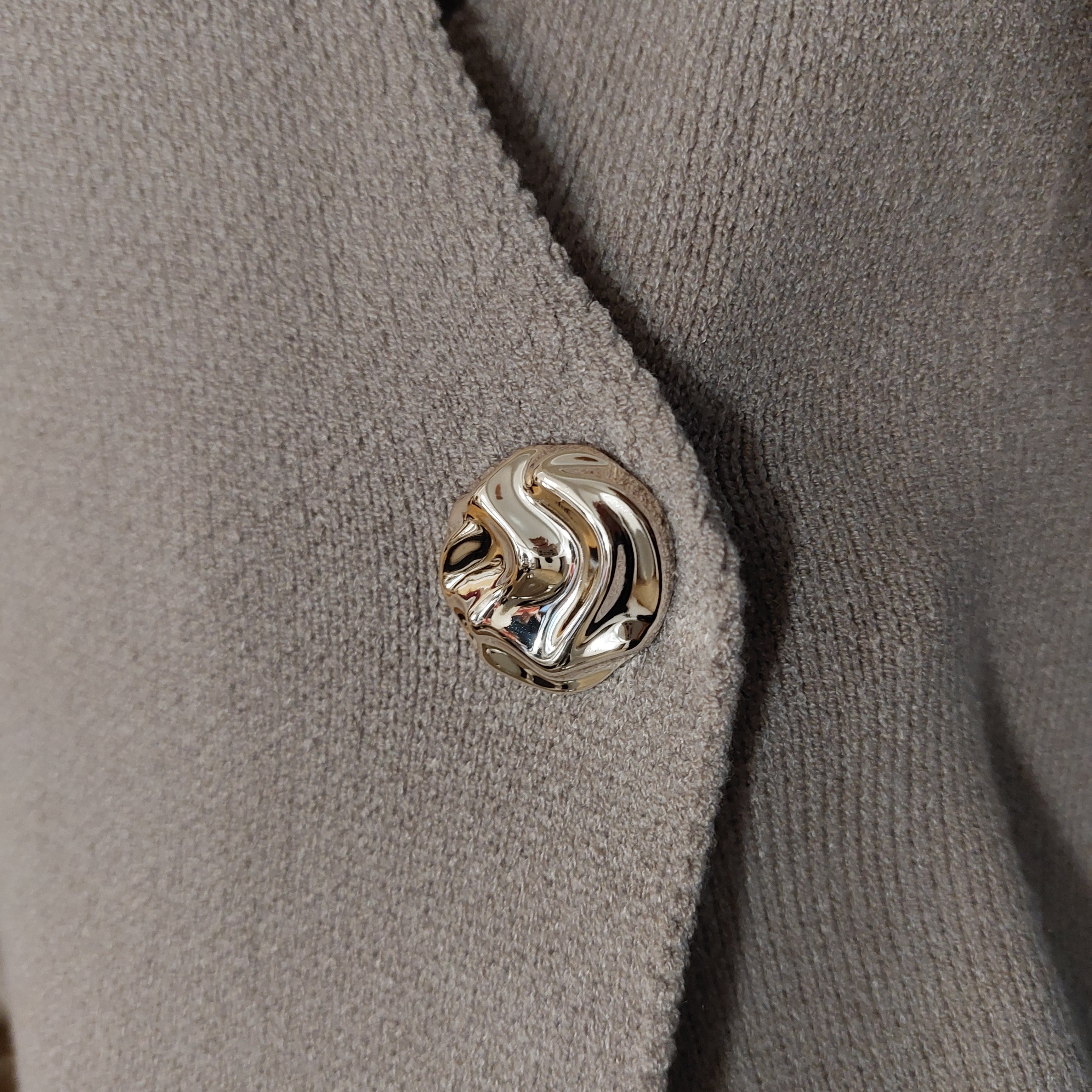 Detail sur le bouton doré du gilet GALA asymétrique sans manches en coloris beige , taille unique 36-42