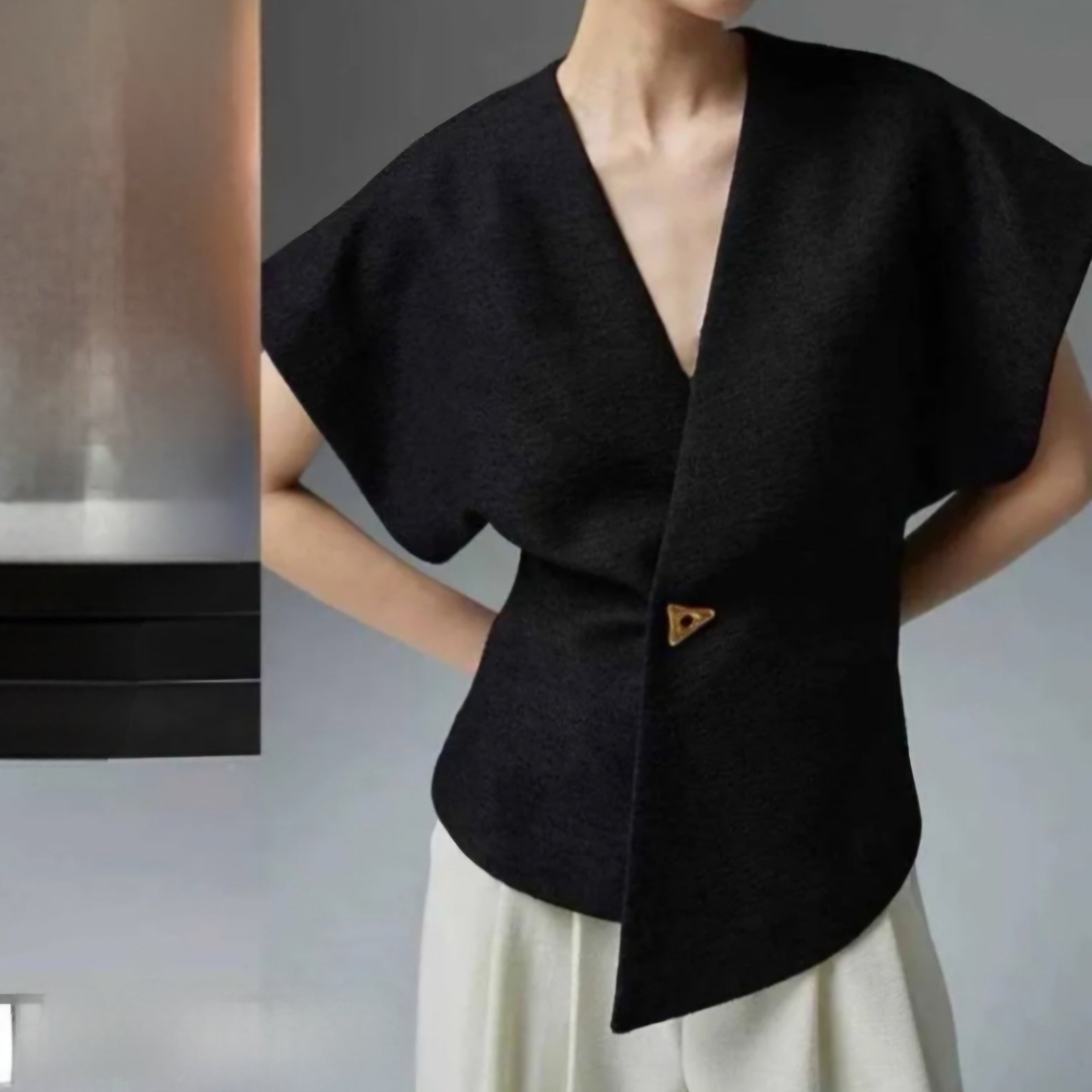 Femme portant le gilet GALA asymétrique sans manches en coloris noir avec bouton doré, taille unique 36-42