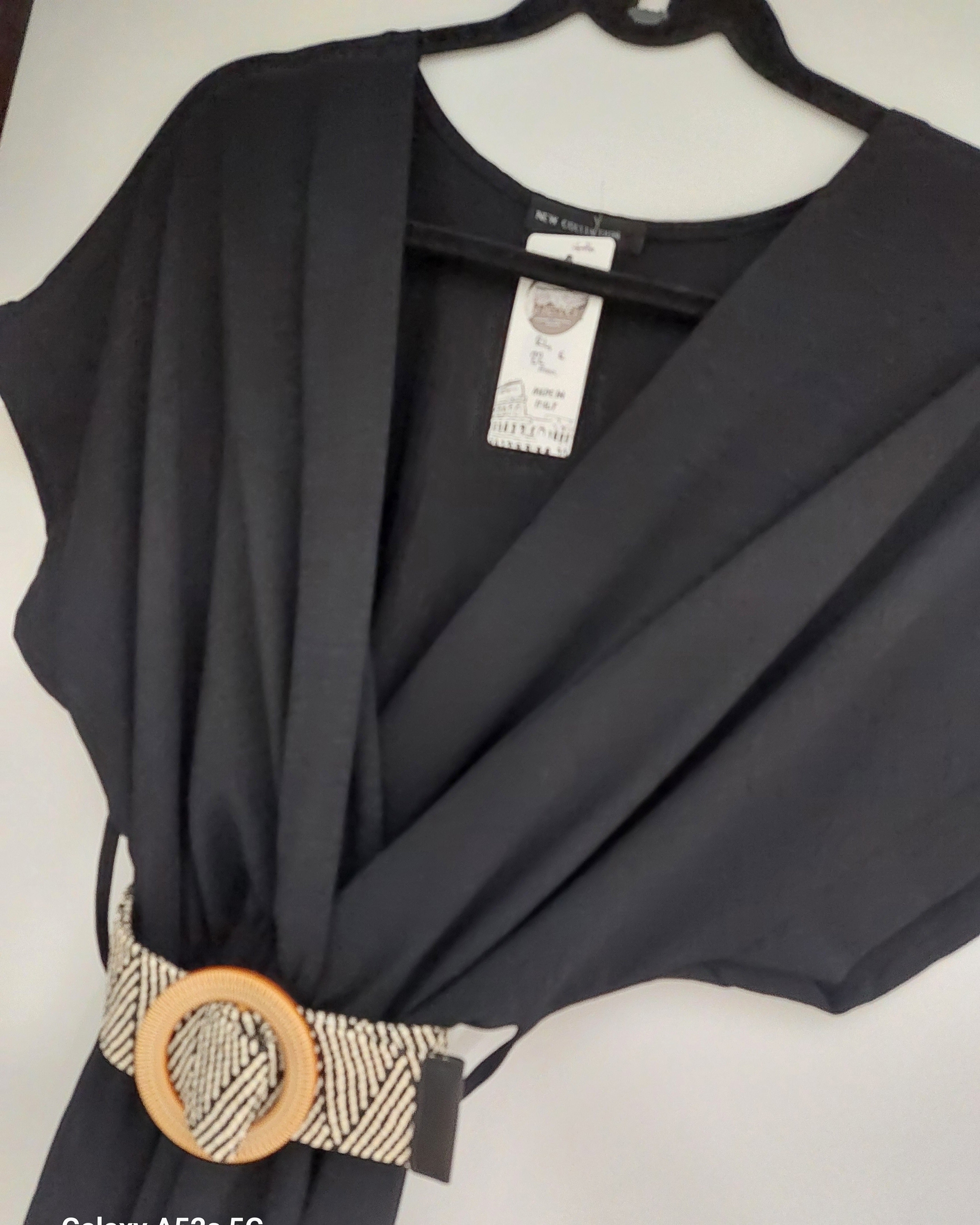 robe longue unie coloris noire et joliement ceinturée en beige sur ceintre. le haut de la robe a une forme kimono et le bas est ample avec du mouvement sur meyreuil