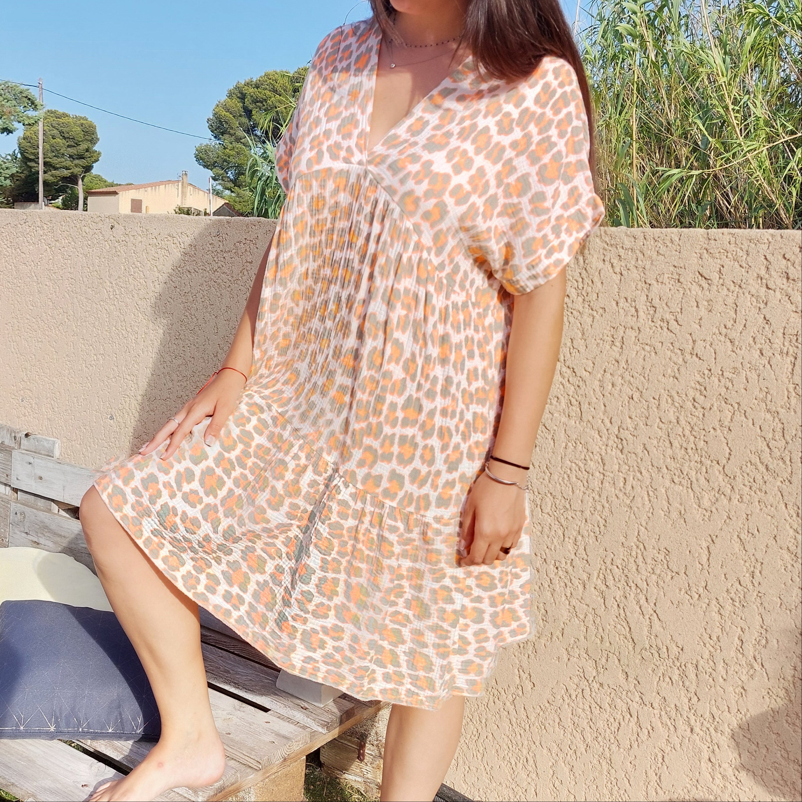 Robe en gaz de coton imprimé léopard dans le orange et kaki sur fond blanc, elle a un col V et elle arrive à hauteur du genou, robe ample manche courte forme kimono sur carry le rouet