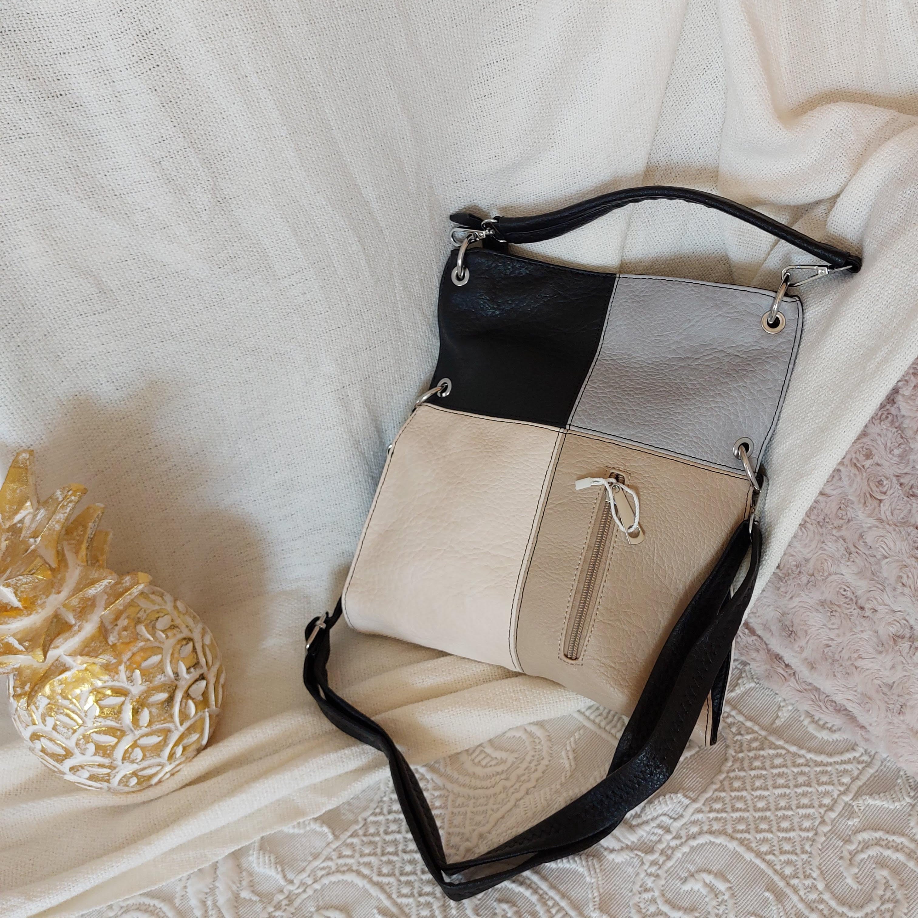 sac simili cuir de forme rectangle à porter en longueur et de 4 couleurs sur la face a savoir (gris clair, noir, beigeet ecru). il possede une grande poche et une petite poche sur la face avant fermant par un zip. des aneaux aciers pour finitions. sur carry le rouet