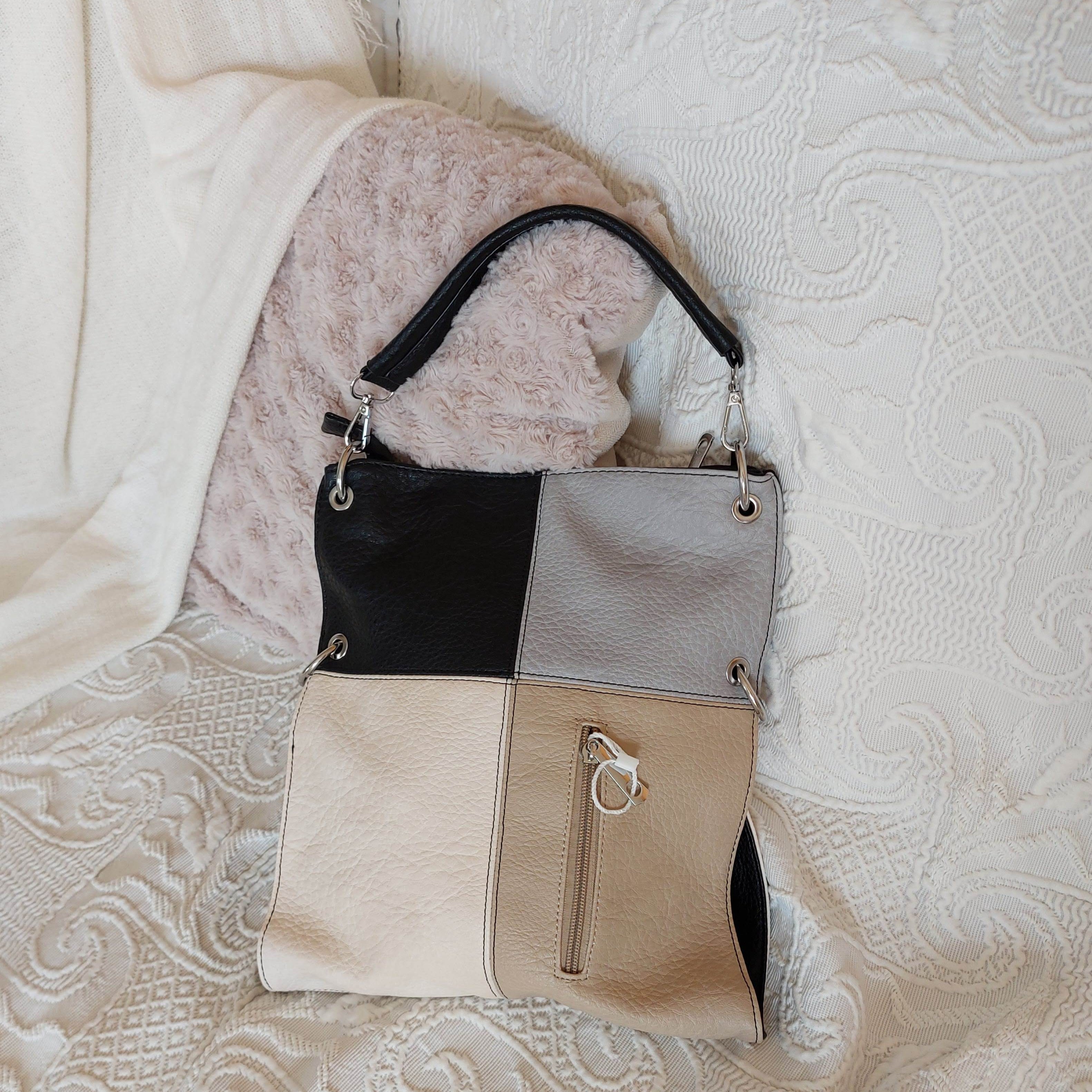 sac simili cuir de forme rectangle à porter en longueur et de 4 couleurs sur la face a savoir (gris clair, noir, beigeet ecru). il possede une grande poche et une petite poche sur la face avant fermant par un zip. des aneaux aciers pour fnitions