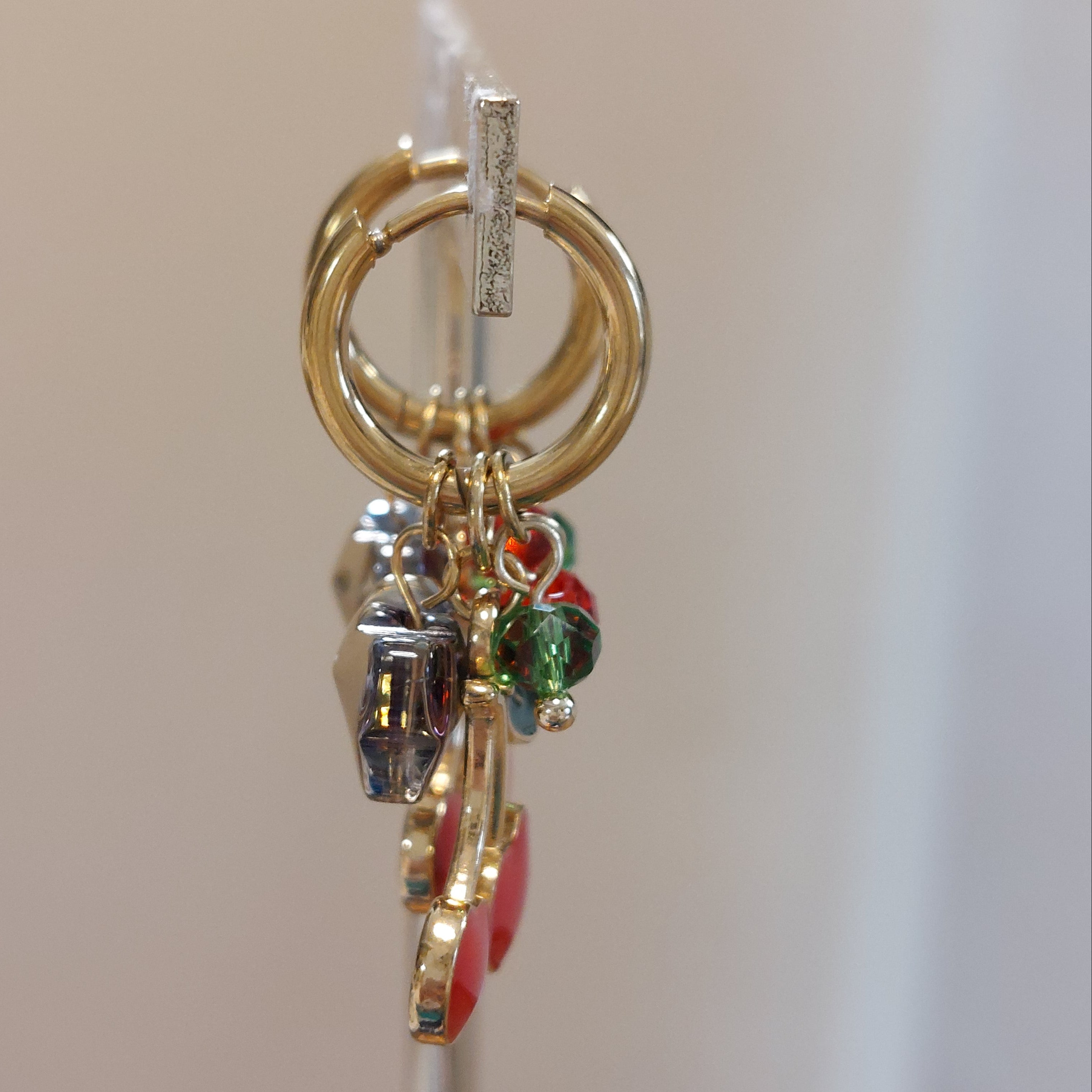 Boucles d’oreilles Soweto vues de côté créoles acier doré avec breloques papillons et cerises