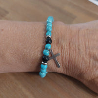 Bracelet Escalet élastiqué en perles de turquoise semi-précieuses avec perles noires, perles plates acier et pampille croix acier