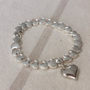 Bracelet élastiqué constitué de perles aciers en forme de petits coeurs bombés et fini par une pampille aussi en forme de coeur bubble sur sausset les pins