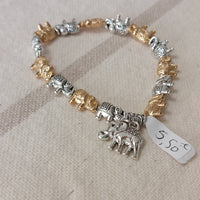 Bracelet élastiqué constitué de perles aciers en forme de petits éléphants dorés et argentés et fini par une pampille aussi en forme d'éléphant argent sur carry le rouet