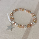 Bracelet élastiqué constitué de perles aciers en forme de petites étoiles bombées dorées et argentées et fini par une pampille aussi en forme d'étoile à cinq branches argent et plate sur carry le rouet