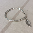 Bracelet élastiqué constitué de perles aciers en forme de petites feuilles rainurées et fini par une pampille aussi en forme de feuille rainurée en noir sur marignane