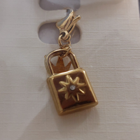 charm ou breloque avec un petit fermoir pour ajouter à un collier où à un bracelet en accumulation personnalisé. il represente un cadenas doré et son petit brillant en acier inoxydable sur marignane