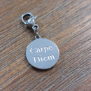 charm ou breloque avec un petit fermoir pour ajouter à un collier où à un bracelet en accumulation personnalisé. il represente une pastille ronde couleur argent gravé Carpe diem  en acier inoxydable sur carry le rouet