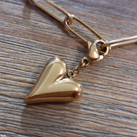 charm ou breloque avec un petit fermoir pour ajouter à un collier où à un bracelet en accumulation personnalisé. il represente un coeur dodu et doré en acier inoxydable sur martiues