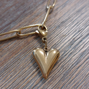 charm ou breloque avec un petit fermoir pour ajouter à un collier où à un bracelet en accumulation personnalisé. il represente un coeur doré et bombé en acier inoxydable sur carry le rouet