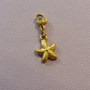 charm ou breloque avec un petit fermoir pour ajouter à un collier où à un bracelet en accumulation personnalisé. il represente une étoile de mer dorée en acier inoxydable sur carry le rouet 