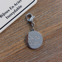 charm ou breloque avec un petit fermoir pour ajouter à un collier où à un bracelet en accumulation personnalisé. il represente une pastille ronde sur laquelle est gravé le message Carpé diem en acier inoxydable sur chateauneuf les martigues