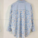 Chemise elina coupe droite manches longues au niveau des cuisses et arrondie sur les côtés.  Elle est en popeline de coton imprimé petite fleur bleu ciel et beige sur fond blanc. Vue de dos dont le haut est en jean clair le col la couture boutonnée et les poignées sont aussi en jeans clair. Habillé du 36 au 42 sur Carry le rouet