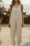 Combinaison longue Cléo ecrue portée en terrasse avec vue mer — col V, décolleté dos, bretelles fines, coupe loose, jambes resserrées à la cheville, 2 poches, taille unique 36/42 — ineva
