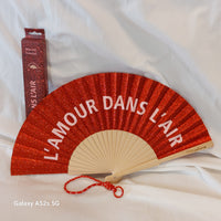 Eventail paillettes bois Evail rouge ouvert message L'Amour dans l'Air écrit en blanc avec dragonne et boite d'emballage - ineva