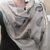 foulard porté et on peut voir de belles feuilles couleur caffé et dorés sur un fond taupe.