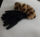 paire de gants posé sur un support ecru. ces gants sont en matière suédne noire rehaussé d'un poigné en fourreau leopard matière fausse fourrure