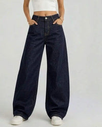 Jean ballon Liam denim brut indigo foncé face – coupe taille haute ample, coutures camel contrastantes, poches avant, porté avec crop top blanc
