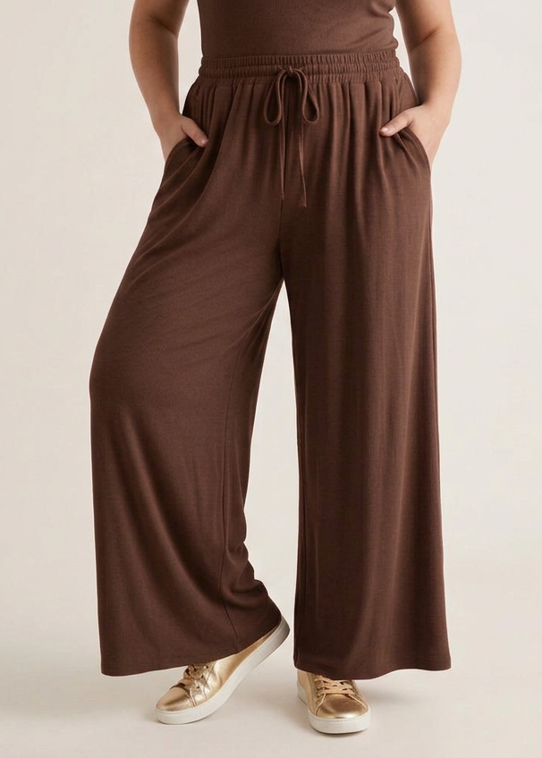 Pantalon grande taille Marlo choco porté de face, coupe large et taille élastiquée, avec les mains dans les poches
