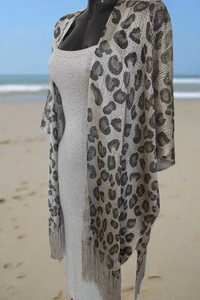 paréo en filet brillant et extensible coupe poncho ouvert devant et finition franges sur le bas. celui ci est porté sur une jupe et un crop top mais il peut aussi etre porté sur un maillot de bain. coloris argent brillant sur carry le rouet