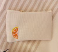 Mini pochette en tissu polyester  de 16 cm sur 10 cm unie ecrue avec un quartier d'orange brodé dans le coin gauche de la face avant . fermeture zip sur le dessus