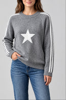 Pull Noel gris porté, col rond, étoile devant et bandes blanches sur les manches
