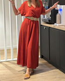 robe longue unie coloris terracotta et joliement ceinturée en beige portée au bureau avec de jolies mules beiges. le haut de la robe a une forme kimono et le bas est ample avec du mouvement  ur aix en provence