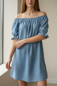 Robe courte Zoé lyocell aspect jean portée par une jeune femme en version épaules Marilyn — col large élastique — look glamour casual chic — ineva
