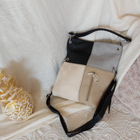 sac simili cuir de forme rectangle à porter en longueur et de 4 couleurs sur la face a savoir (gris clair, noir, beigeet ecru). il possede une grande poche  et une petite poche sur la face avant fermant par un zip. des aneaux aciers pour finitions. sur carry le rouet