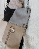 sac simili cuir de forme rectangle à porter en longueur et de 4 couleurs sur la face a savoir (gris clair, noir, beigeet ecru). il possede une grande poche  et une petite poche sur la face avant fermant par un zip. des aneaux aciers pour fnitions