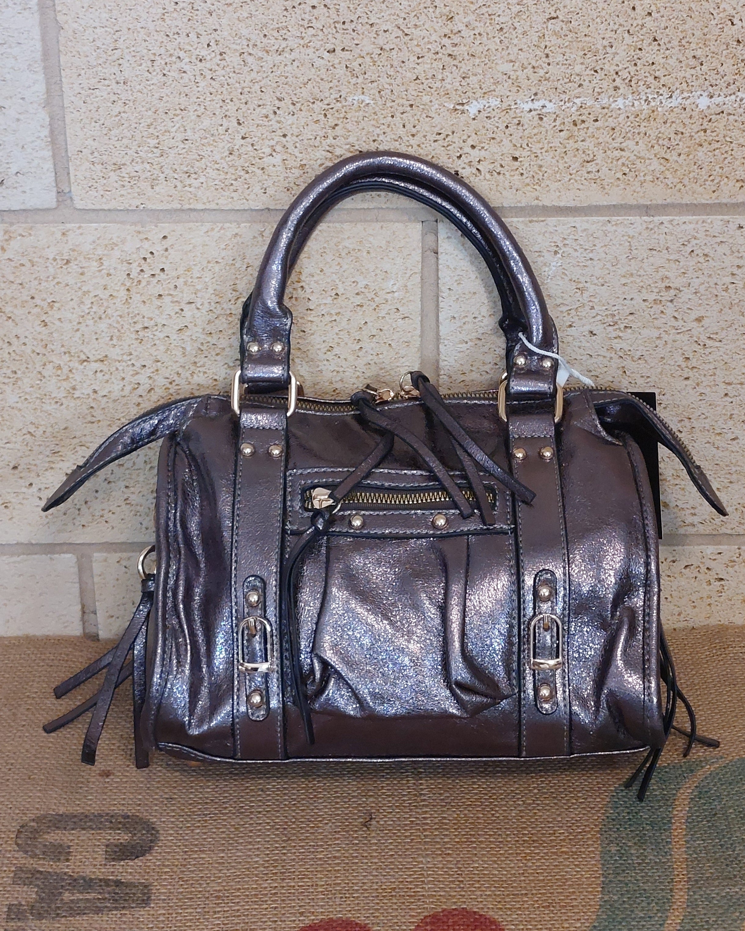 Sac Azilal simili cuir brillant métallisé bronze vue de face — forme bowling, double poignée courte, poche zip frontale, clous et boucles dorés, 28x20 cm — ineva
