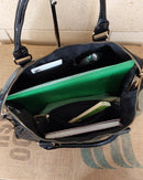 Intérieur du Grand Sac Bologne simili cuir brillant irisé noir en situation — cahier A4, carnet, trousse, grand compartiment avec poches zip, sac de cours ou week-end — ineva
