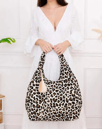 Sac de plage Payo toile de jute motif léopard porté à la main — bijou coquillages et pom-pons sur l'anse — look bohème estival femme — ineva
