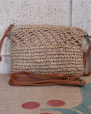 Pochette Porto raphia posée à plat – vue face et bandoulière simili cuir camel amovible, fermeture zip dorée
