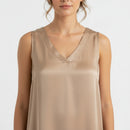 Top sans manches forme débardeur coloris camel satiné sur l'avant en col V et ample porté par une jeune femme 
