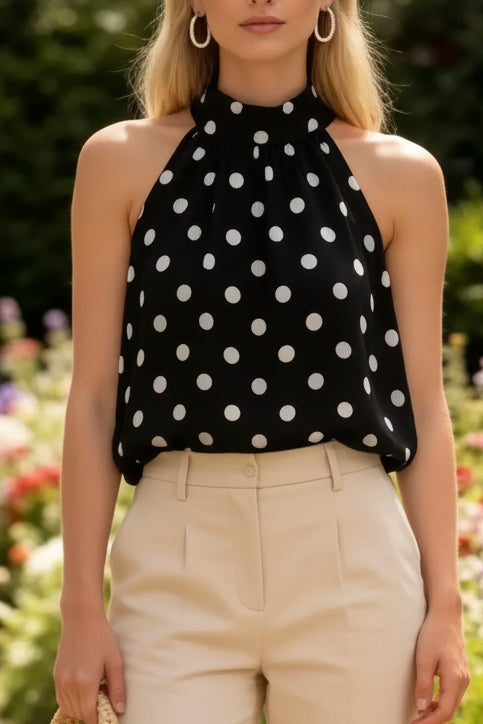 Top trapèze Charles noir à pois blancs porté de face – col halter à nouer, coupe ample sans manches, voile doublé, associé à un pantalon beige
