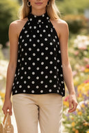 Top trapèze Charles noir à pois blancs porté en marche – col halter froncé, coupe fluide ample, voile polyester doublé, panier rotin, jardin fleuri
