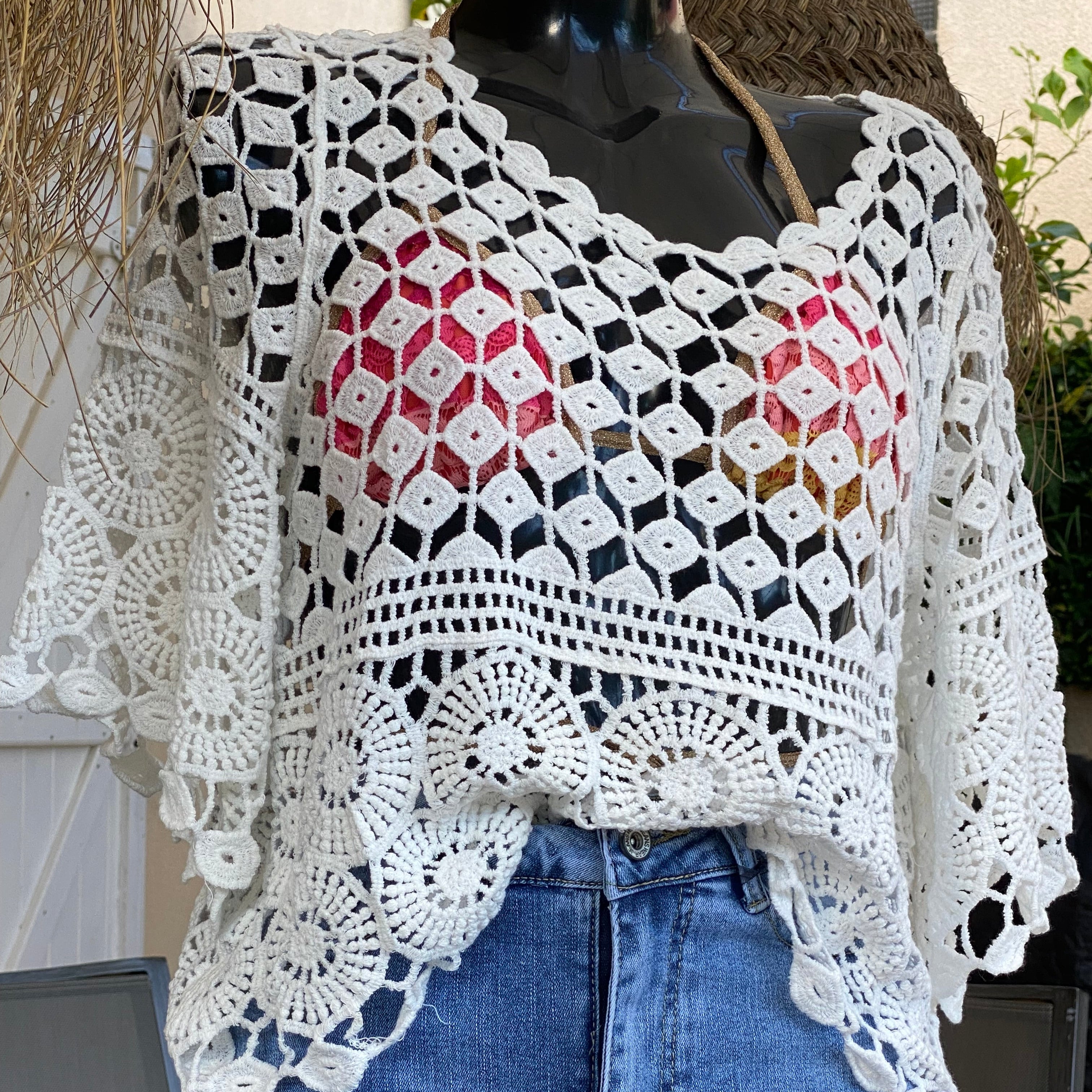 Top en crochet blanc ajouré motif rsace sur le bas et damier au dessus de la poitrine. les manches sont de formes evasées sur et 3/4. il est porté sur une jupe en jean et un haut de maillot de bain doré qui donne  une jolie transparence . musthave et look boheme sur carry le rouet