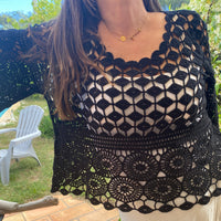Top en crochet noir ajouré motif rsace sur le bas et damier au dessus de la poitrine. les manches sont de formes evasées sur et 3/4. il est porté sur une robe blanche à bretelle ce qui donne une jolie transparence . musthave et look boheme sur carry le rouet